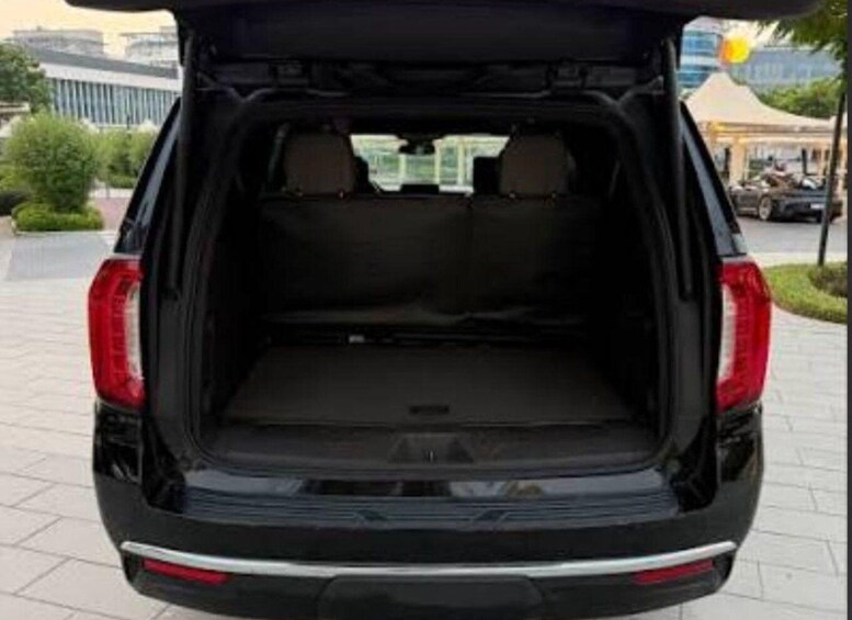 The rear of a black SUV with an open trunk, a visible license plate, and a rearview mirror. 2