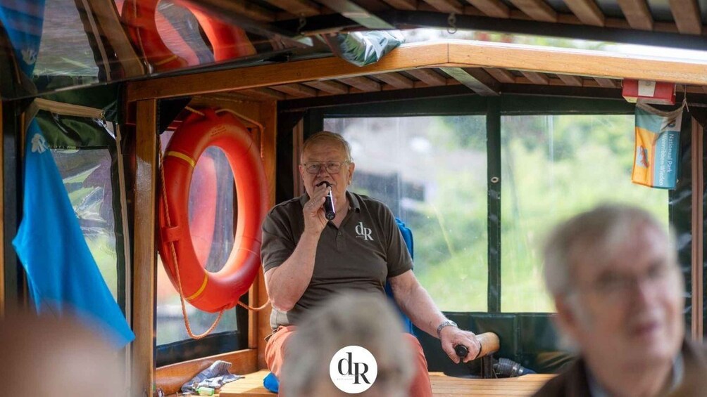 A person speaking into a microphone inside a boat with a life preserver hanging on the wall. 5