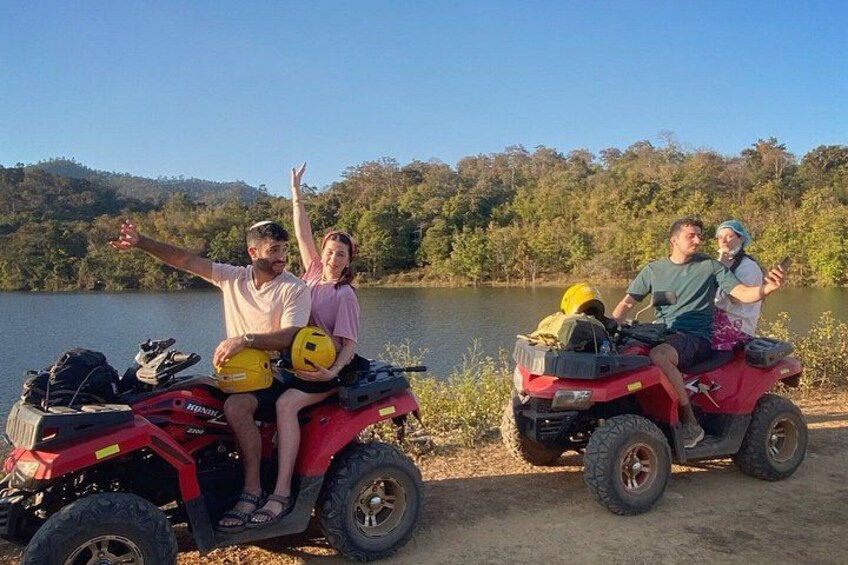 Two people on a red ATV, one pointing, and a lake in the background. 5