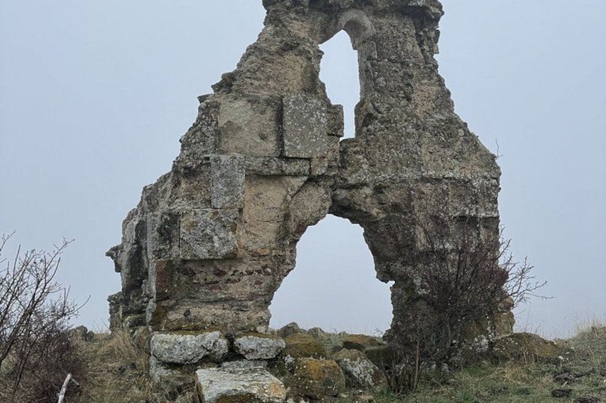 A large stone arch structure with visible erosion and overgrowth. 3