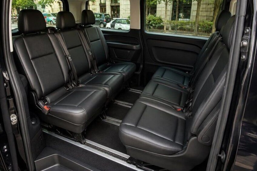 A vehicle interior with black leather seats, a center console, and a rearview mirror. 2