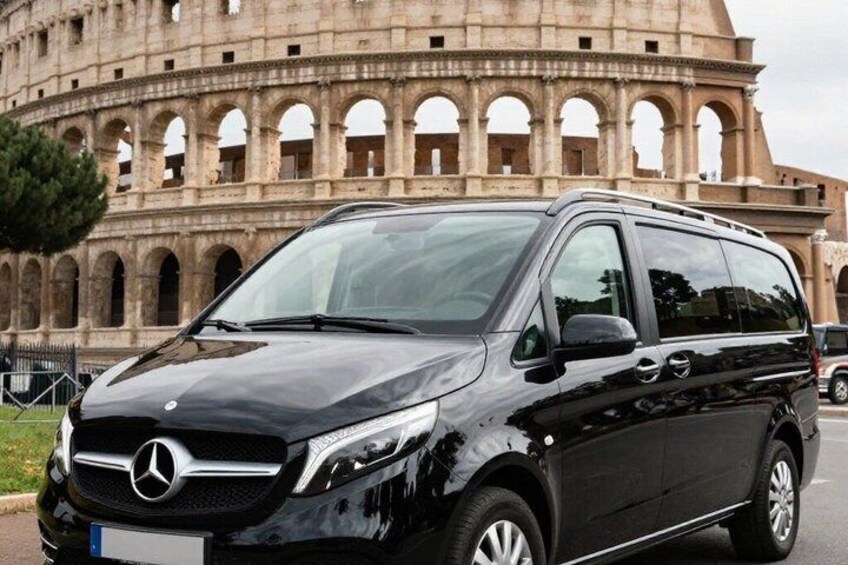 A black Mercedes van parked in front of the Colosseum. 1
