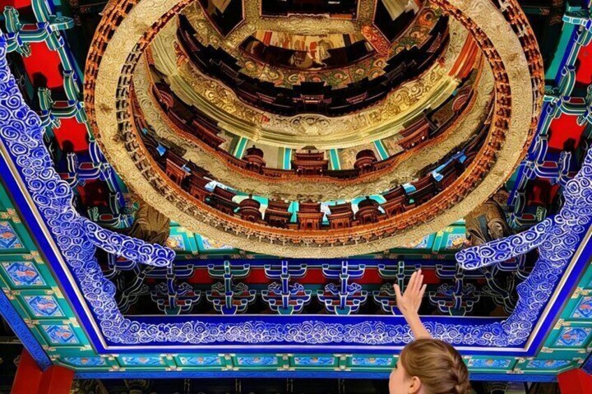 A grand, ornate theater with a circular design and intricate blue and gold patterns on the ceiling. 2