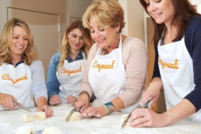 Four people wearing aprons with the word 'Corymeal' on them, working with dough on a table. 1