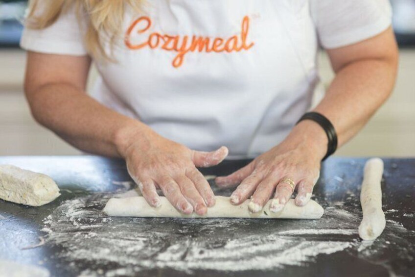 A person rolling out dough on a floured surface. 4