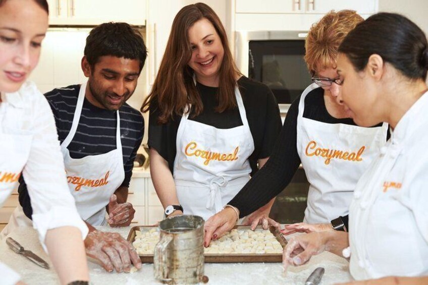 A group of people wearing aprons with the word 'Corymeal' on them, working together in a kitchen environment. 2