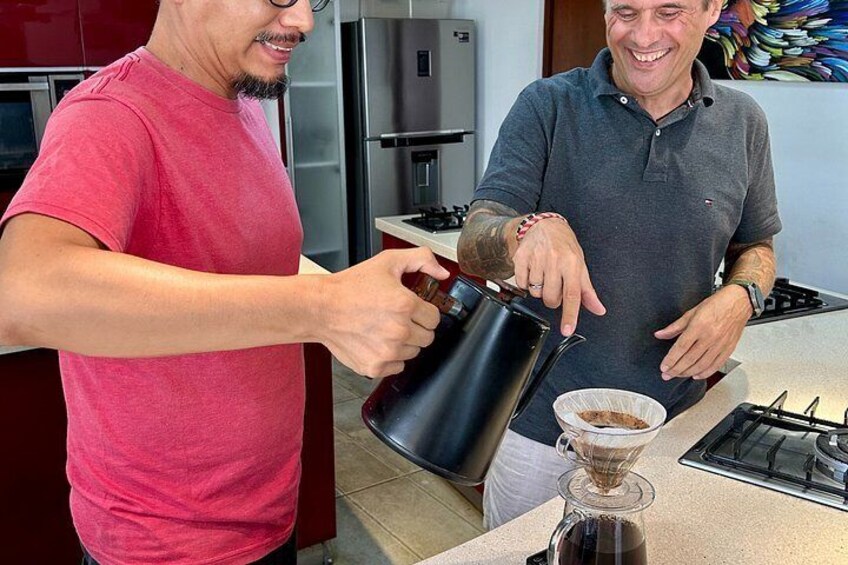 Two people in a kitchen, one pouring coffee into a cup. 2
