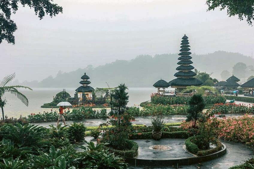 A pagoda, a person with an umbrella, and a body of water. 1