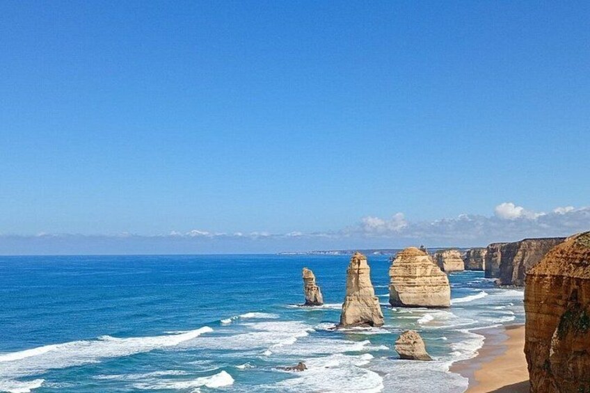 A coastal landscape with prominent rock formations and a clear blue sky. 4