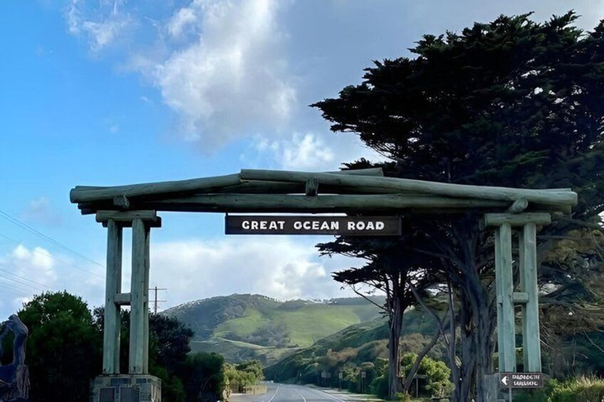 A sign for Great Ocean Road with a wooden archway and a view of the landscape. 2