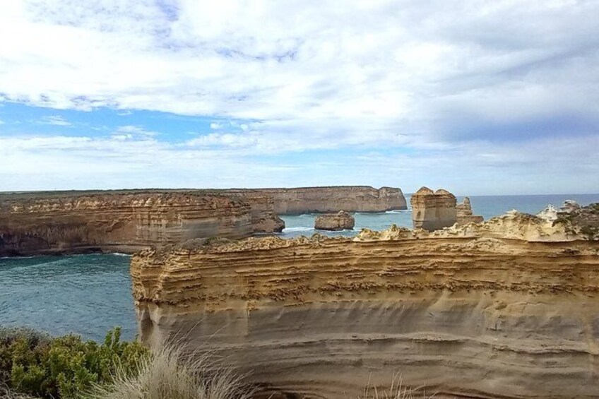 A coastal cliff with layered rock formations and a clear sky. 4