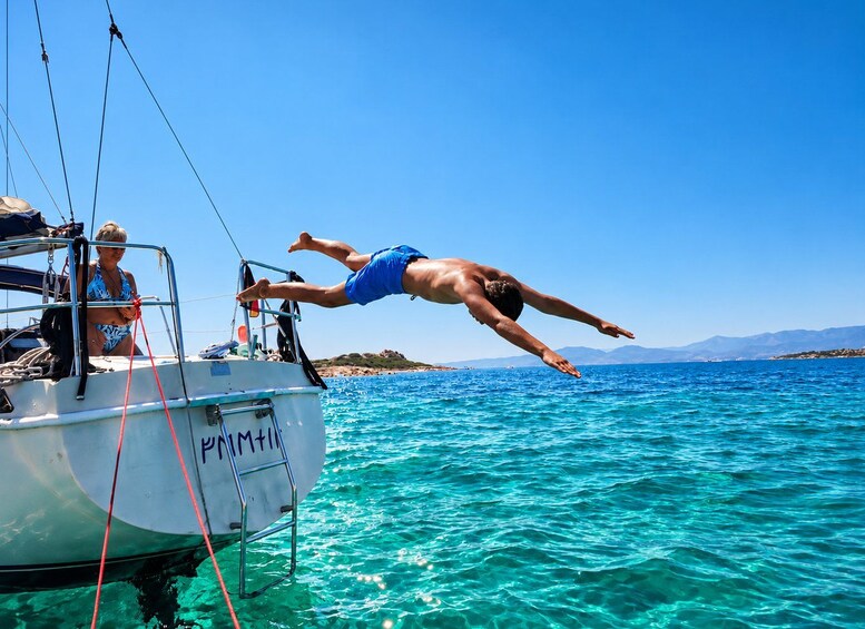 A person diving from a boat into clear blue water. 5