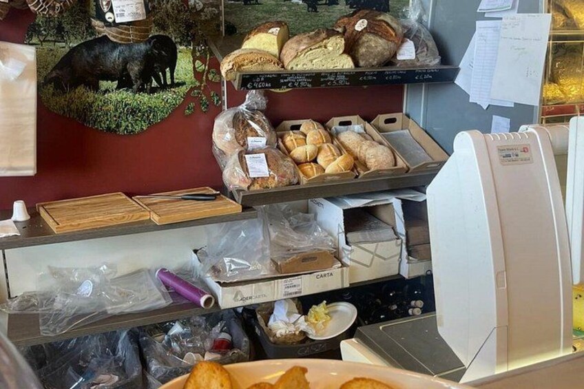 A bakery display with bread and pastries, a cash register, and a cash box. 3