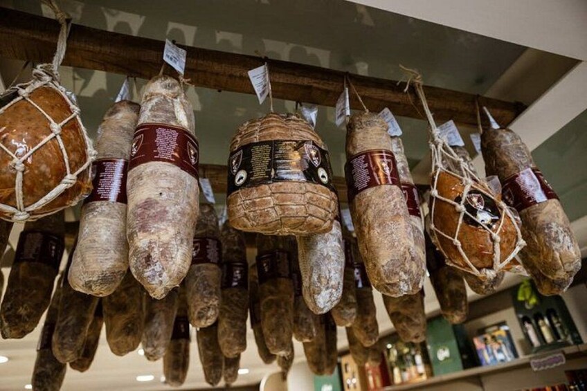 Various types of cured meats hanging in a shop. 1