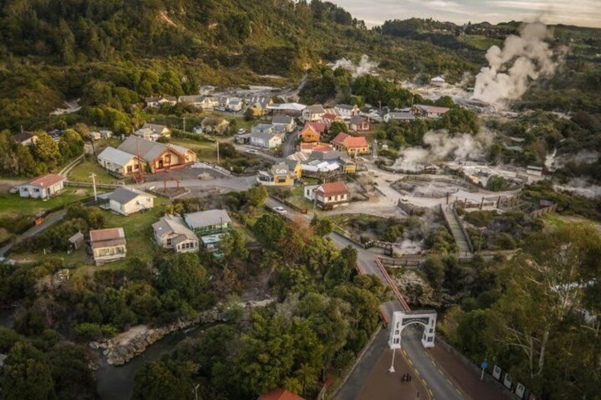 A town with houses, a road, and a river. There are buildings with chimneys emitting smoke. 4