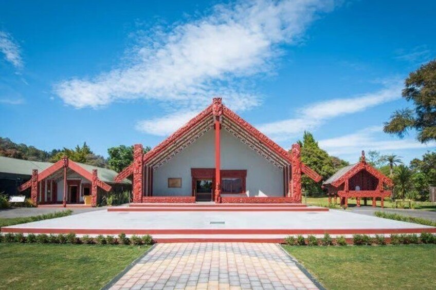 A traditional red-roofed building with a central entrance, surrounded by a paved walkway and greenery. 4