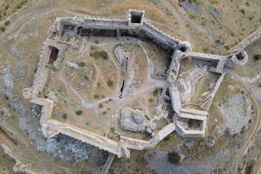 An aerial view of an ancient fortified structure with walls, a central courtyard, and scattered ruins. 5