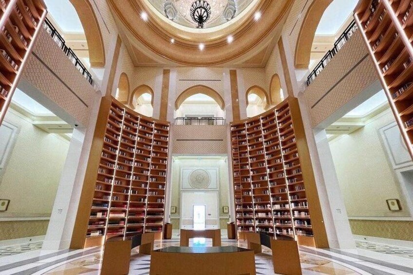 A grand library with tall bookshelves, arched ceilings, and a central fountain. 2