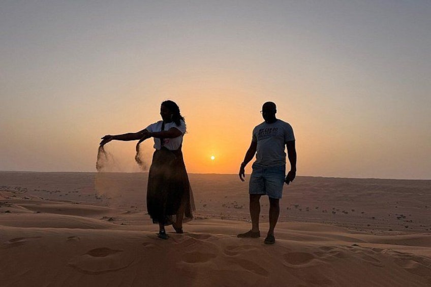 Two people walking on a sandy beach at sunset. 1