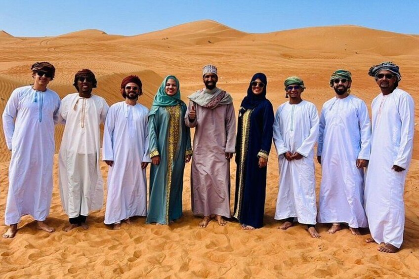 A group of people standing in a desert with sand dunes in the background. 3