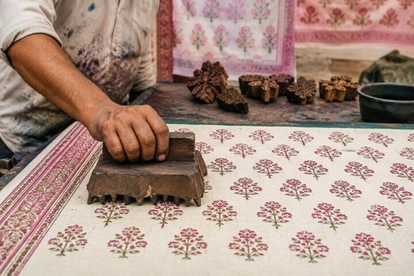 A person using a wooden stamp on a patterned fabric. 2