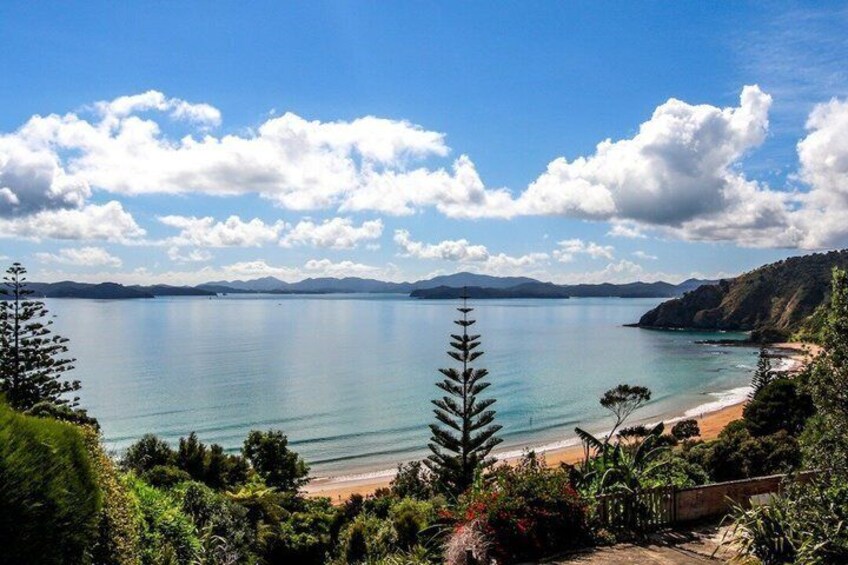 A coastal landscape with a beach, clear water, and distant mountains. 4