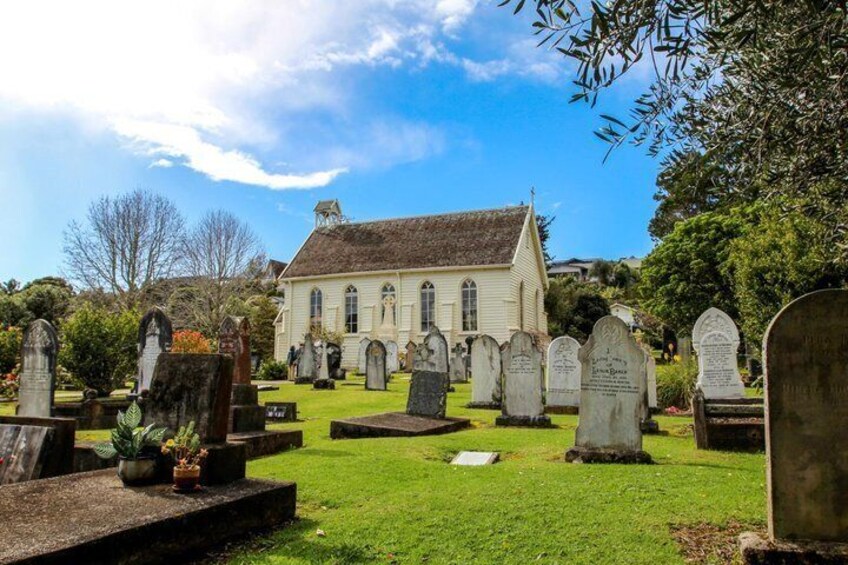A cemetery with headstones, a church, and a clear blue sky. 3