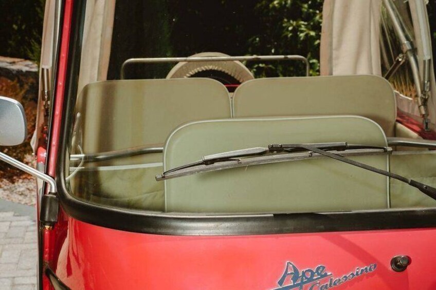 A vintage red car with a convertible top, a windshield wiper, and a side mirror. 4
