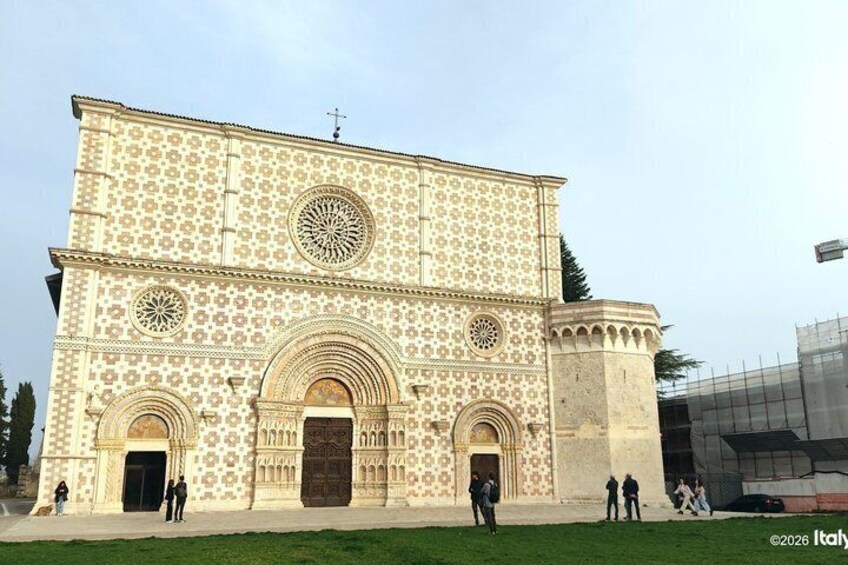 A large building with intricate tile patterns, arched doorways, and a prominent circular window. 1