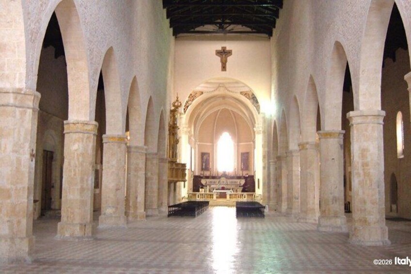 An interior of a cathedral with arched ceilings, a central altar, and a cross above. 3
