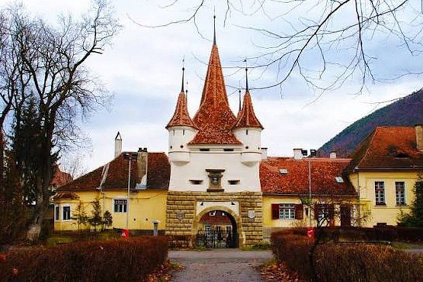 A castle with three towers, a central archway, and a surrounding garden. 2
