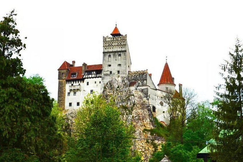 A historic castle with multiple towers, surrounded by lush greenery. 3