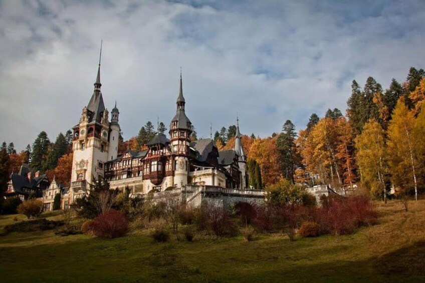 A large, historic building with multiple towers and spires, surrounded by autumn-colored trees. 5