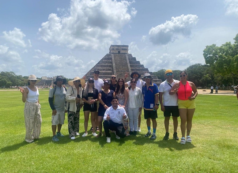 A group of people posing in front of a large pyramid structure on a sunny day. 4