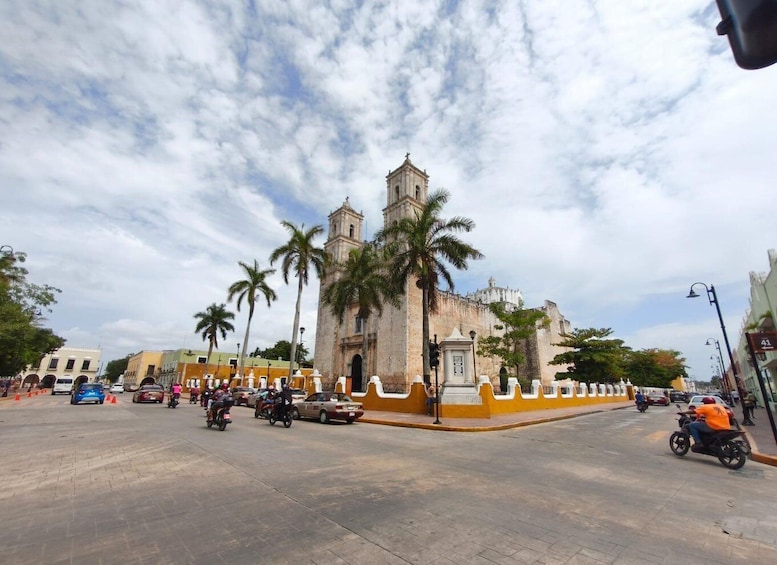 A busy street with a historic building, palm trees, and parked cars. 1