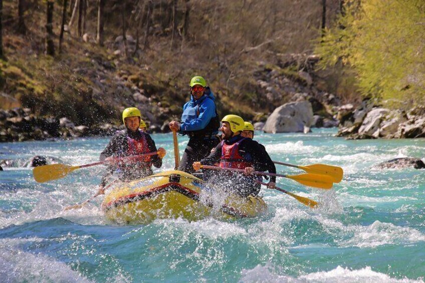 Three people in a yellow raft navigating a river with rapids, surrounded by rocky terrain and sparse vegetation. 1