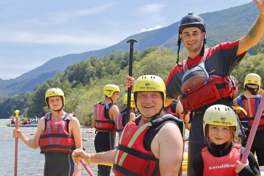 People in life vests and helmets on a river, paddles in hand, with mountains in the background. 5