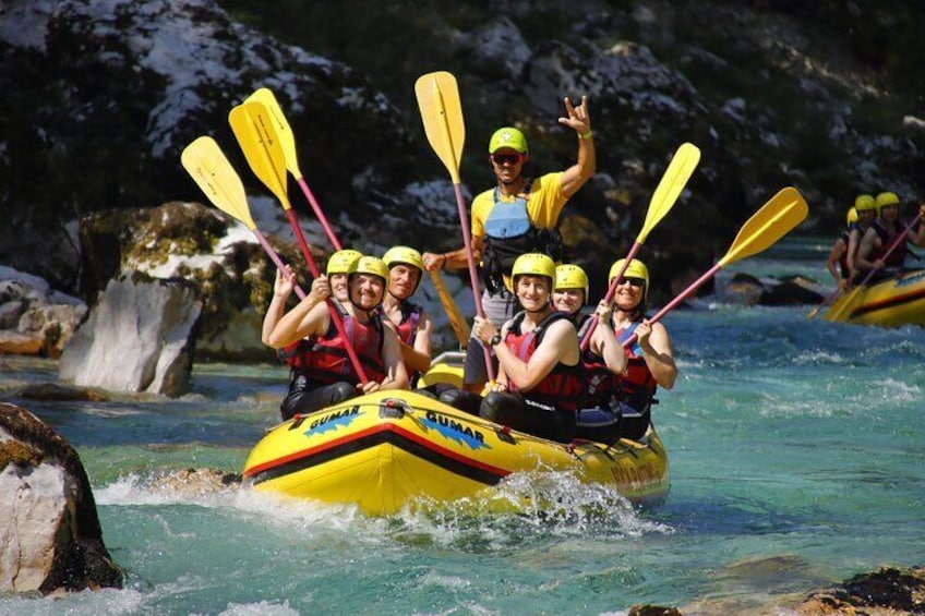 A group of people in a yellow raft with paddles, navigating through a river with rocks and clear water. 2