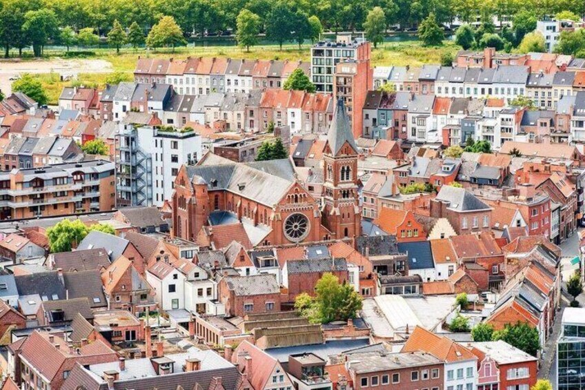 A densely packed urban area with historic buildings, a prominent church with a tall spire, and a mix of residential and commercial structures. 1