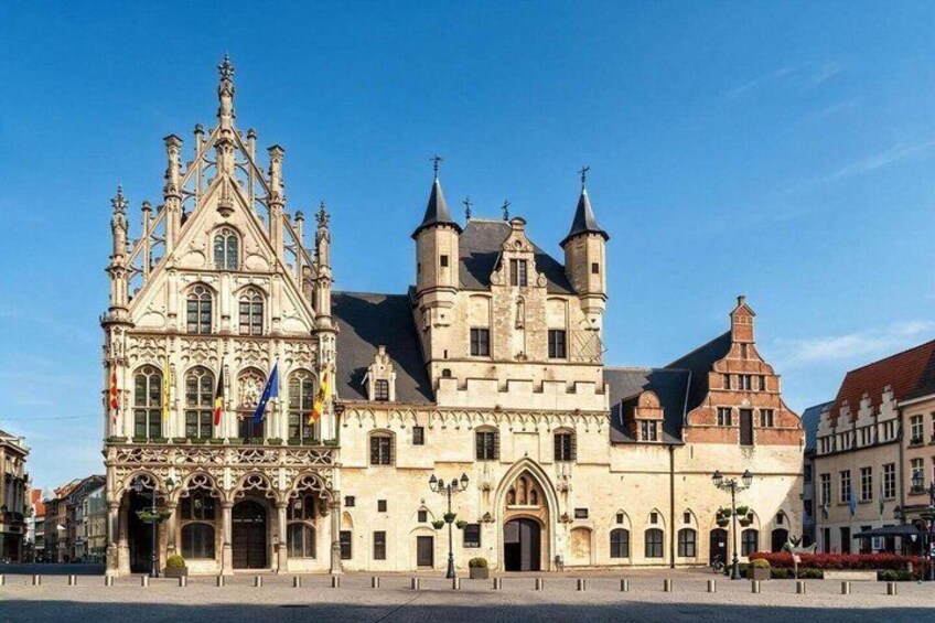 A historic building with intricate architecture, a prominent tower, and a clear blue sky. 4