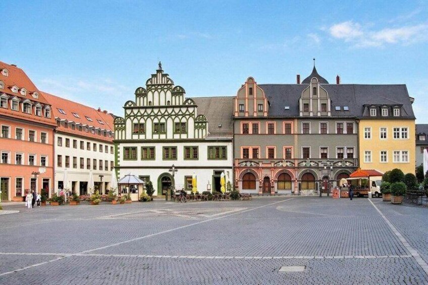 A historic European square with colorful buildings, cobblestone pavement, and a central fountain. 4