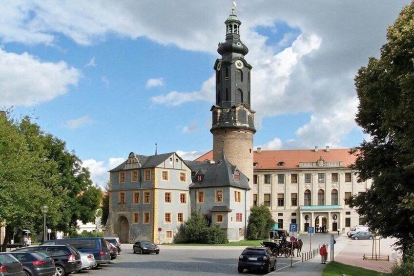 A historic building with a clock tower, parked cars, and a clear sky. 3