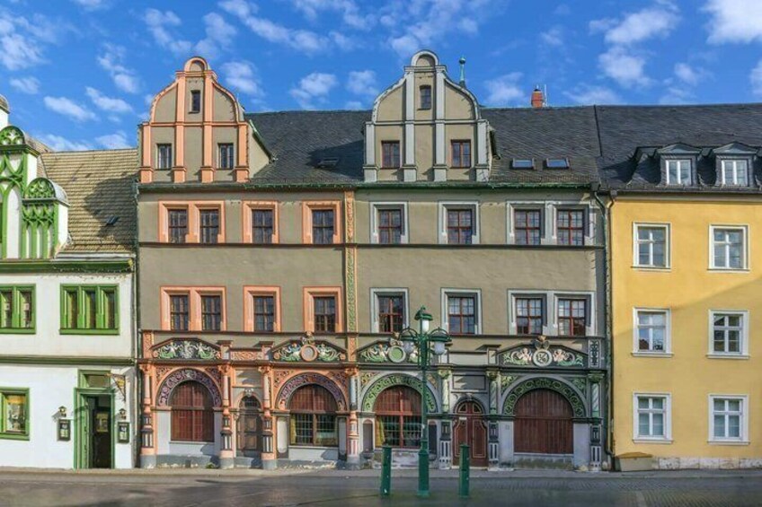 A row of colorful buildings with ornate facades and green doors. 2