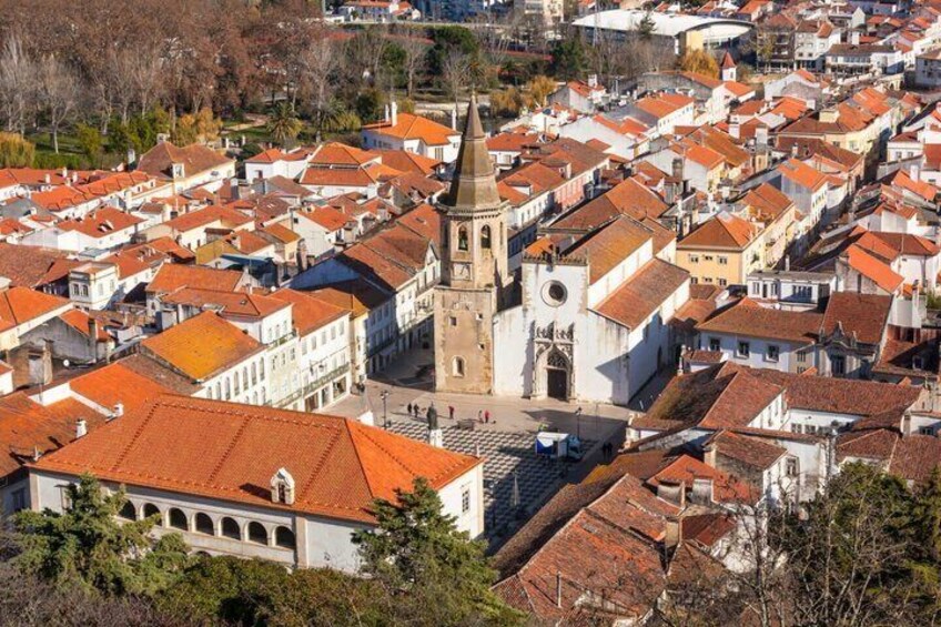 A town with red-tiled roofs, a prominent church tower, and a mix of white and red buildings. 1