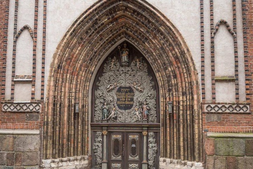 Una entrada en estilo gótico con un arco ornamentado y trabajos de metalería, así como un escudo de armas. 5