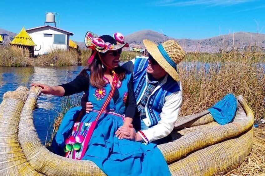Two people in a traditional boat on a river, surrounded by reeds and a small building in the background. 1