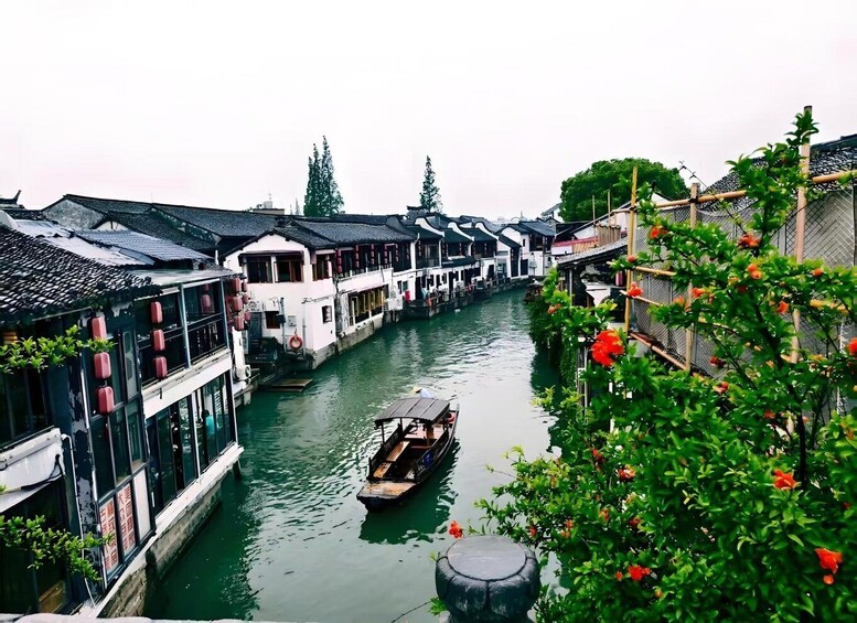 A narrow waterway flanked by traditional buildings with red lanterns, a boat, and lush greenery. 5