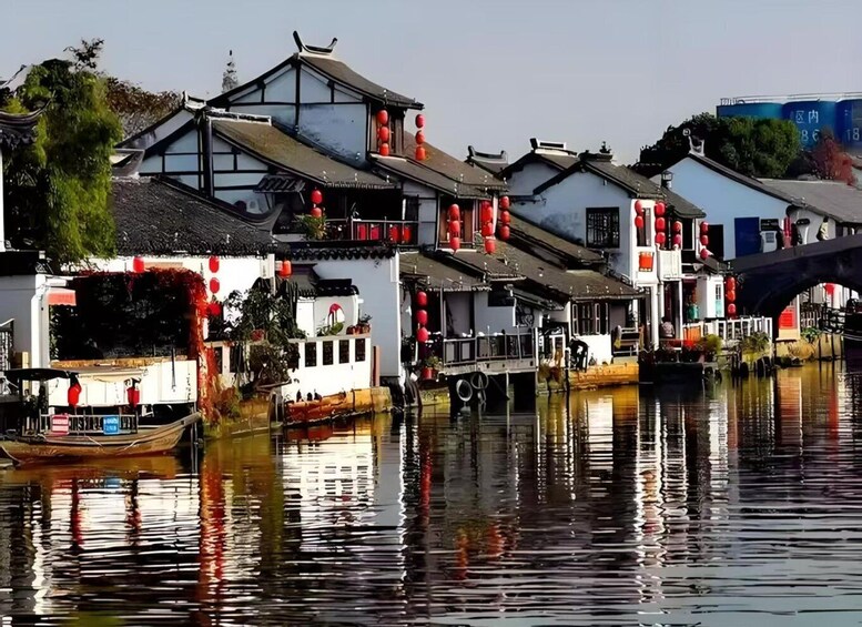 Traditional buildings with red lanterns, a boat, and a bridge over calm water. 3
