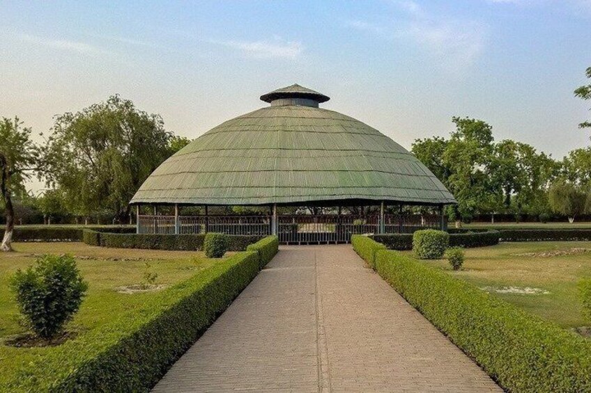 A large, green-roofed pavilion with a paved walkway leading to it, surrounded by neatly trimmed hedges and trees. 5