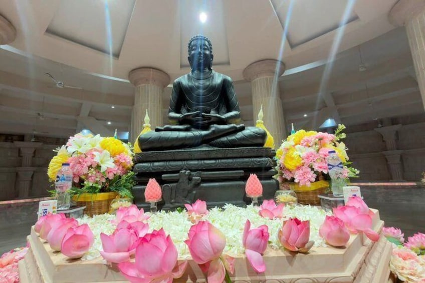 A seated Buddha statue surrounded by flowers and lotus petals. 1